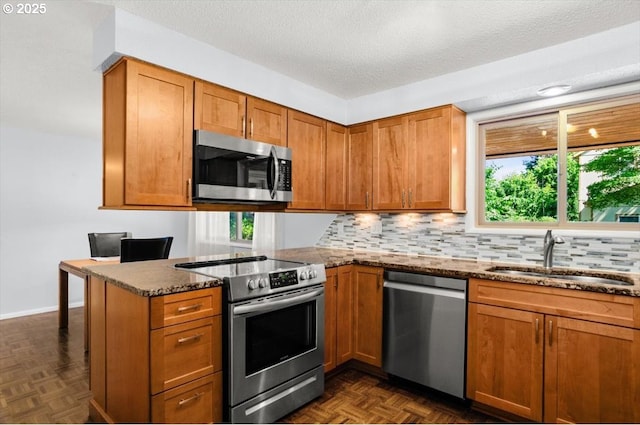 19555 SW Cascadia St, Beaverton, OR 97078 - kitchen featuring appliances with stainless steel finishes, a sink, dark stone countertops, plenty of natural light, and a textured ceiling