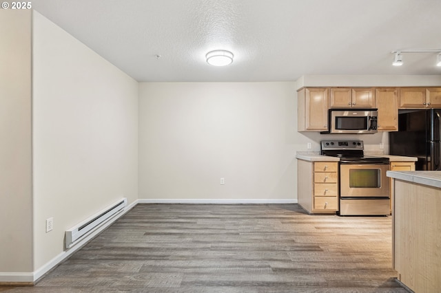 kitchen featuring a baseboard heating unit, light brown cabinetry, appliances with stainless steel finishes, and light hardwood / wood-style flooring