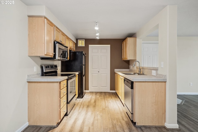 kitchen featuring sink, stainless steel appliances, light wood-type flooring, and light brown cabinetry