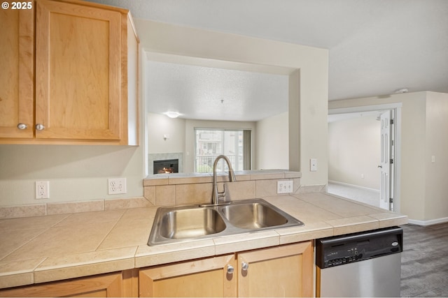 kitchen with sink, tile countertops, stainless steel dishwasher, and kitchen peninsula