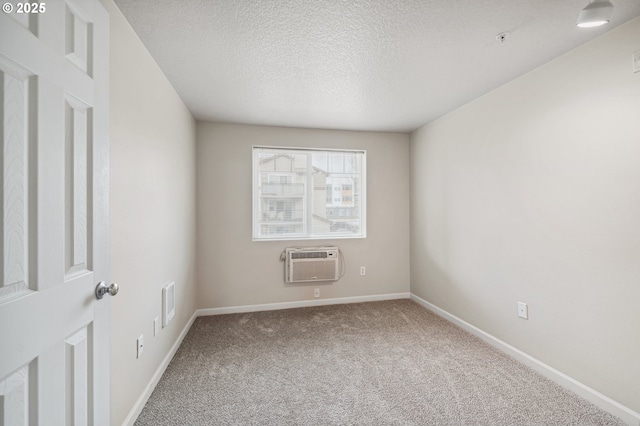 carpeted spare room with a wall unit AC and a textured ceiling