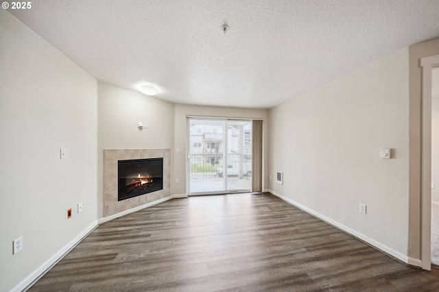 unfurnished living room with a textured ceiling, a tile fireplace, and dark hardwood / wood-style floors