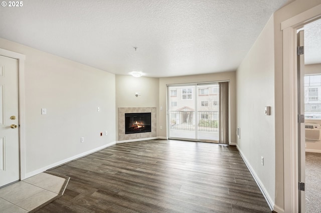 unfurnished living room with a textured ceiling, a tiled fireplace, and hardwood / wood-style floors