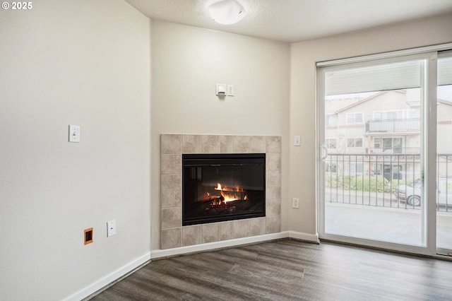 unfurnished living room featuring a tiled fireplace and hardwood / wood-style flooring