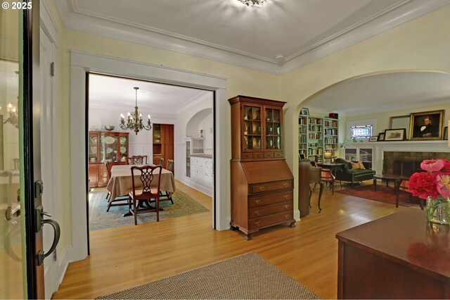 803 NE Laurelhurst Pl, Portland, OR 97232 - foyer entrance with a fireplace, crown molding, light wood-style floors, arched walkways, and a chandelier
