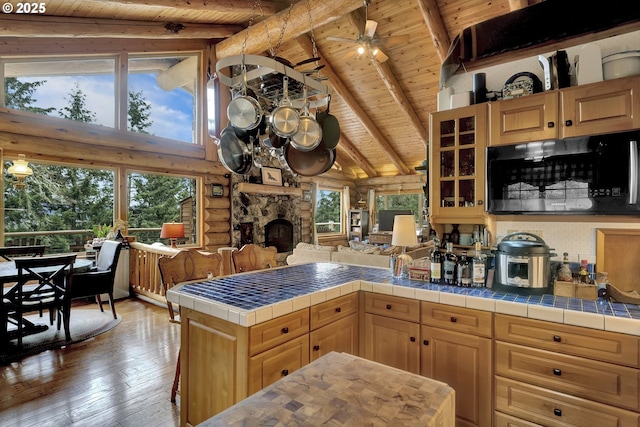 6715 Ivy St, Springfield, OR 97478 - kitchen featuring wood ceiling with exposed beams, light wood-style floors, a peninsula, glass insert cabinets, and a stone fireplace