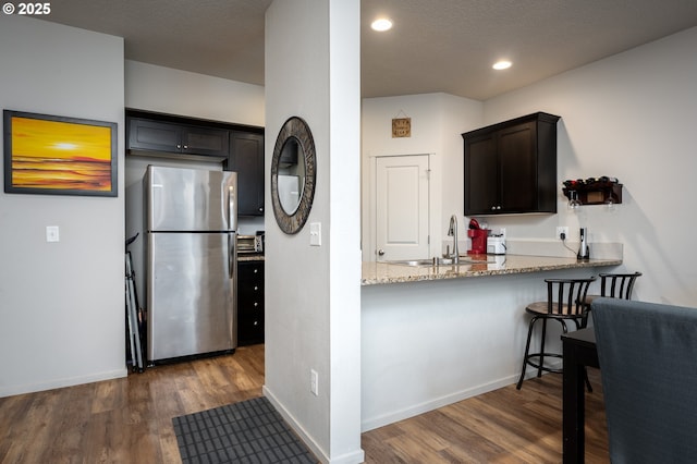 kitchen featuring dark wood-style floors, light stone countertops, baseboards, and freestanding refrigerator