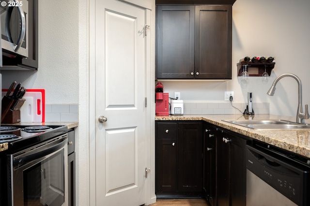 kitchen featuring a sink, stainless steel appliances, and light stone counters