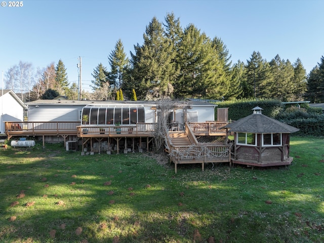 back of property featuring a yard, a gazebo, a sunroom, and a deck