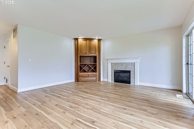 unfurnished living room with light wood finished floors, a fireplace, and baseboards