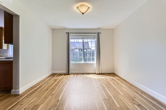 unfurnished room with light wood-type flooring and baseboards