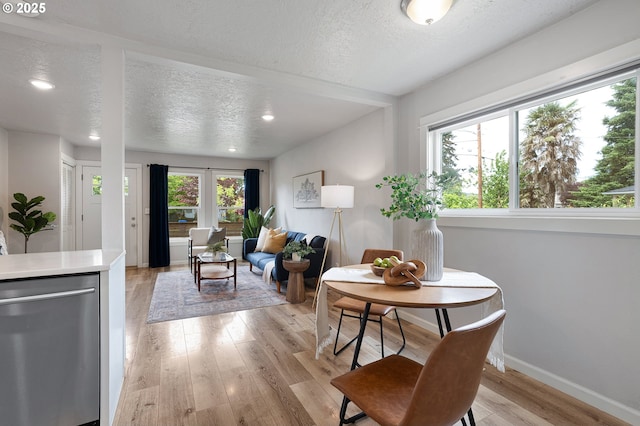 dining area featuring a textured ceiling, light wood-style flooring, recessed lighting, and baseboards