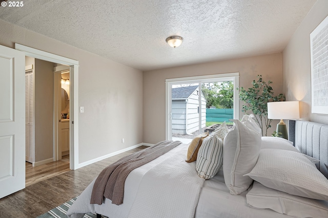 bedroom with access to exterior, wood finished floors, a textured ceiling, and baseboards