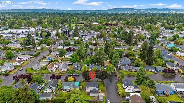 aerial view of property and surrounding area featuring nearby suburban area and a mountainous background