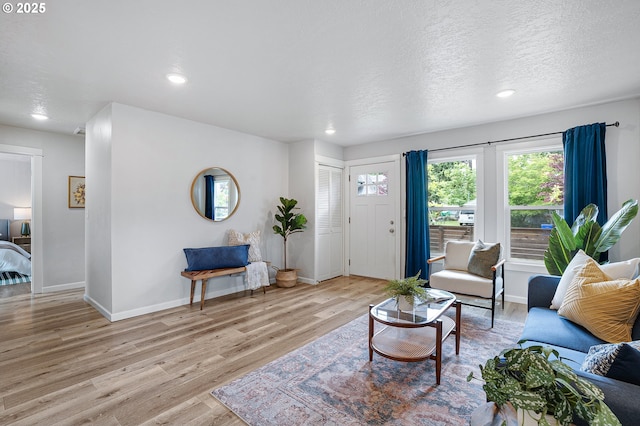 living area with light wood-style floors, baseboards, recessed lighting, and a textured ceiling