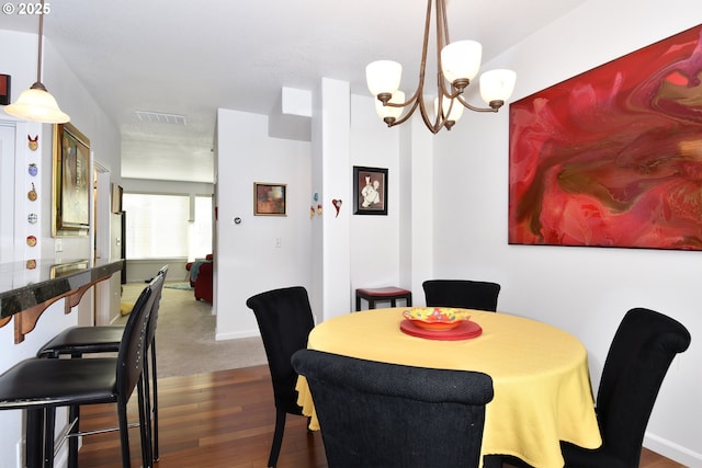 dining space featuring an inviting chandelier, baseboards, wood finished floors, and visible vents