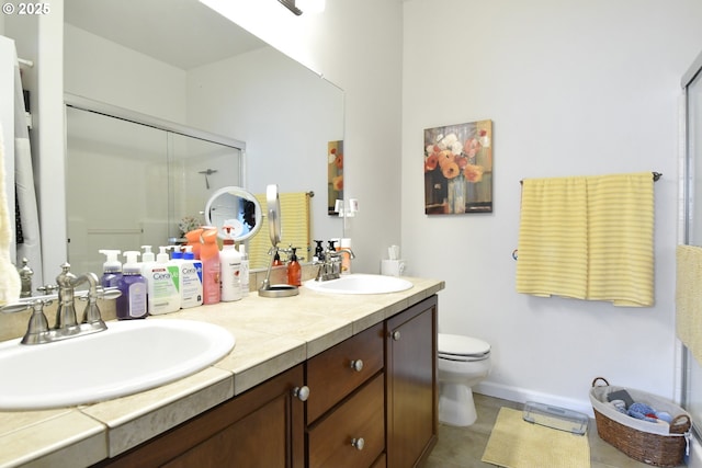 bathroom with a sink, a shower stall, toilet, and double vanity