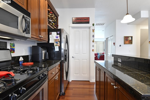 kitchen with visible vents, pendant lighting, brown cabinets, stainless steel appliances, and dark wood-type flooring