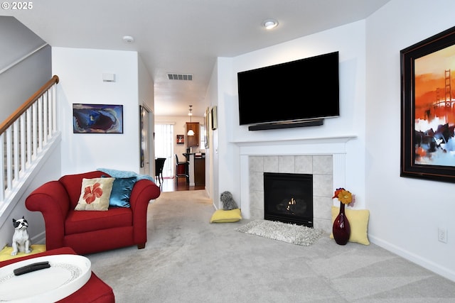 living area with a fireplace, carpet floors, stairs, baseboards, and visible vents