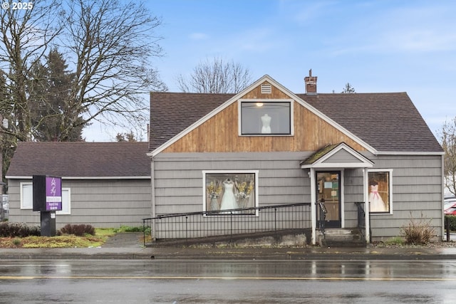 view of front of property with a shingled roof and a chimney