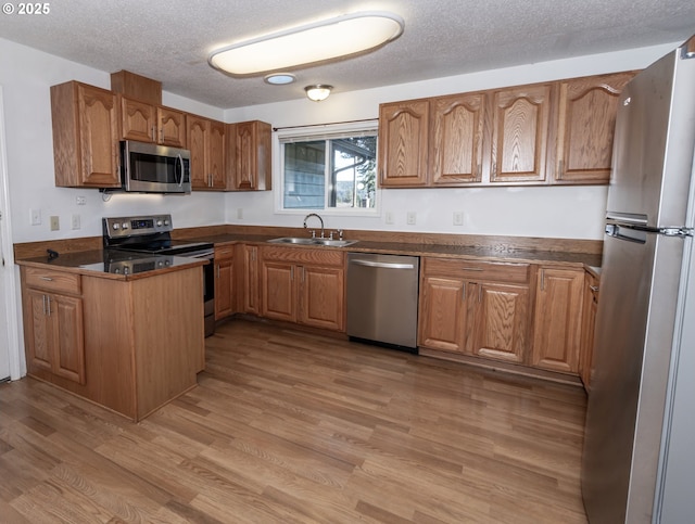 kitchen featuring sink, a textured ceiling, light hardwood / wood-style flooring, and stainless steel appliances