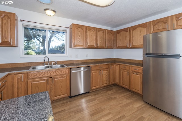 kitchen featuring sink, a textured ceiling, light hardwood / wood-style flooring, and stainless steel appliances