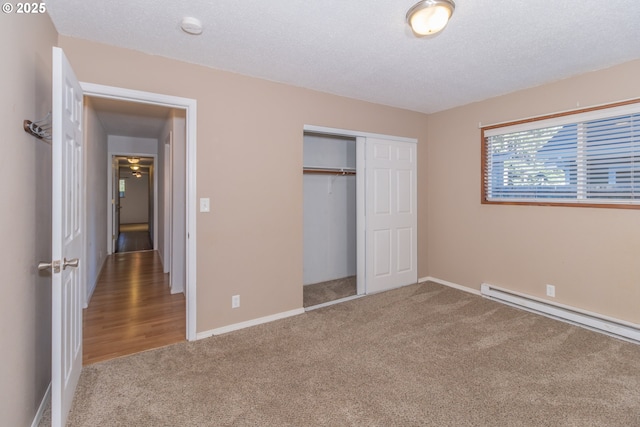 unfurnished bedroom featuring carpet, a baseboard heating unit, a closet, and a textured ceiling