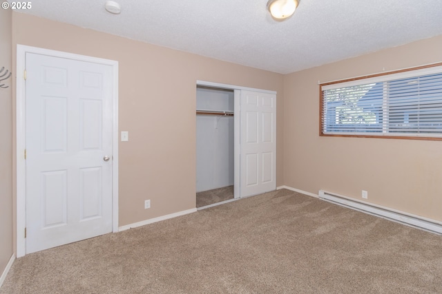 unfurnished bedroom with carpet floors, baseboard heating, a textured ceiling, and a closet