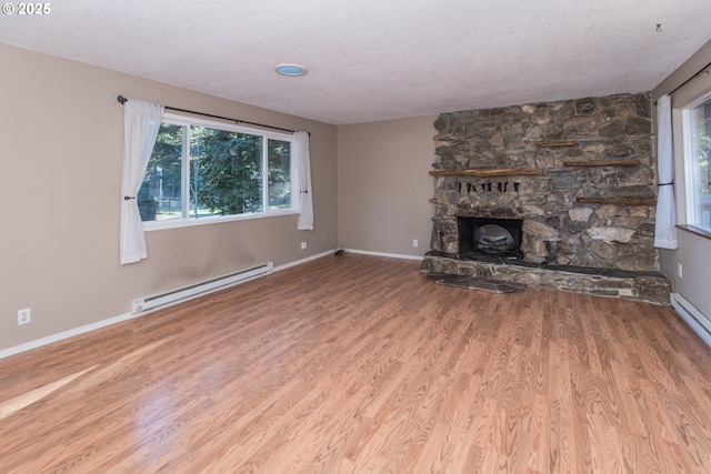 unfurnished living room featuring hardwood / wood-style flooring, baseboard heating, a textured ceiling, and a fireplace