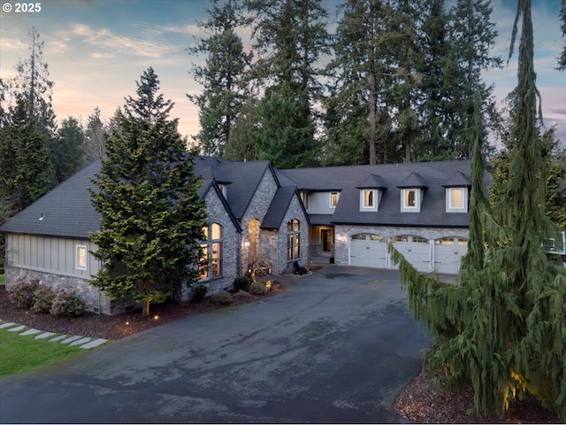 view of front of property with aphalt driveway, stone siding, board and batten siding, and a garage