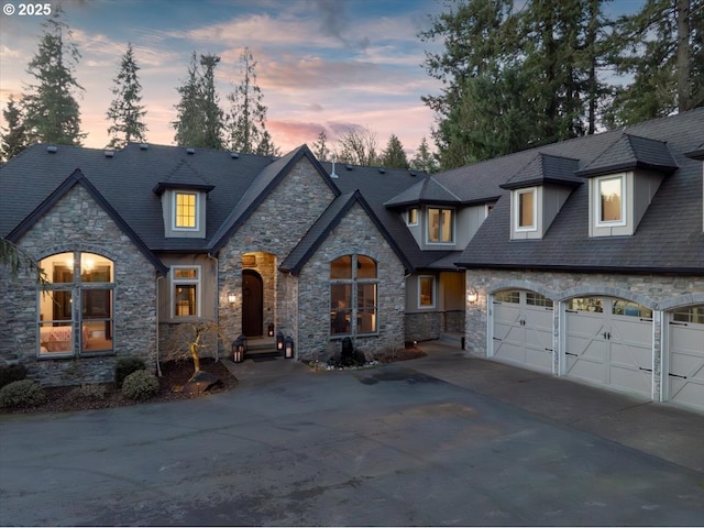 french country inspired facade with a garage and concrete driveway