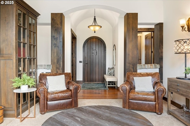 living area featuring arched walkways and wood finished floors