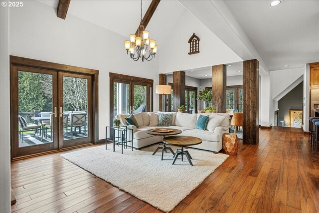 living area featuring high vaulted ceiling, a notable chandelier, french doors, hardwood / wood-style floors, and beamed ceiling