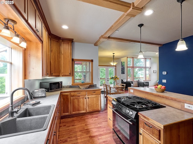 111 5th St, Silverton, OR 97381 - kitchen with black gas stove, a sink, stainless steel microwave, light wood finished floors, and pendant lighting