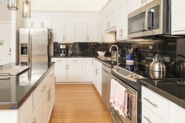 kitchen with appliances with stainless steel finishes, sink, white cabinetry, and backsplash