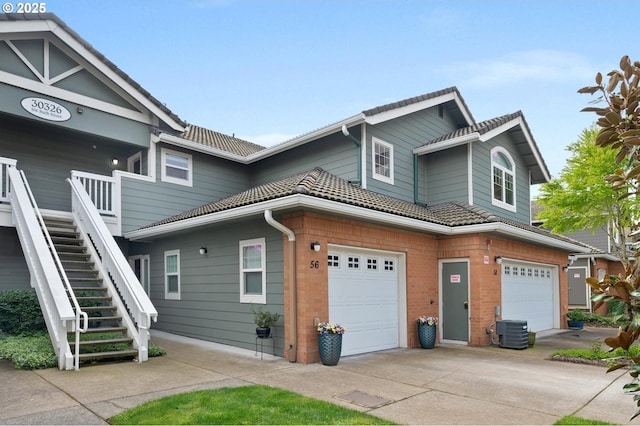 30326 SW Ruth St Unit 58, Wilsonville, OR 97070 - view of side of property featuring central AC unit, stairway, driveway, an attached garage, and brick siding
