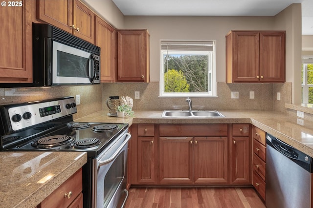 30326 SW Ruth St Unit 58, Wilsonville, OR 97070 - kitchen with brown cabinetry, stainless steel appliances, light wood-type flooring, and a sink