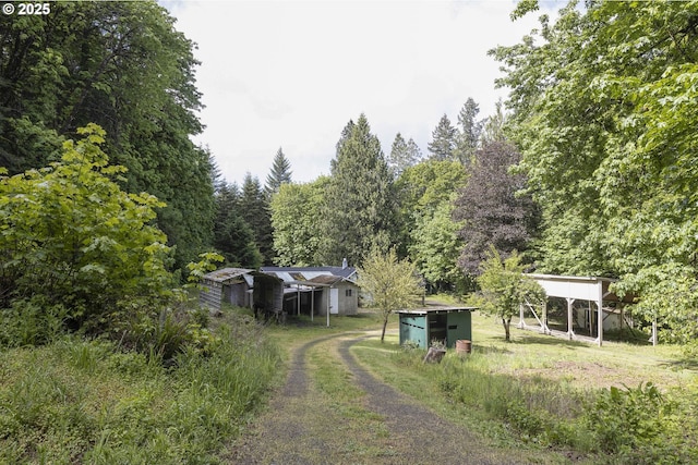18570 Oakdale Rd, Dallas, OR 97338 - view of yard featuring driveway, a detached carport, a wooded view, and an outdoor structure