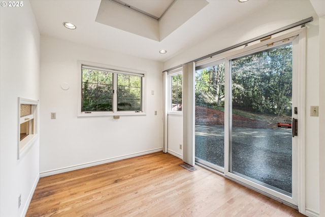 doorway featuring light wood-type flooring and a raised ceiling