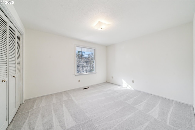 unfurnished bedroom featuring a closet and light colored carpet