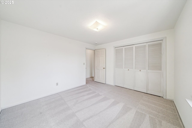 unfurnished bedroom featuring light carpet and a closet