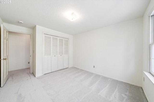 unfurnished bedroom featuring a closet, a textured ceiling, and light colored carpet