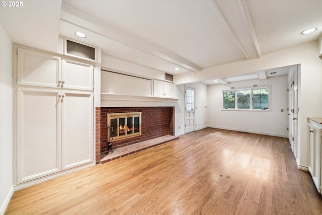 unfurnished living room featuring light hardwood / wood-style flooring, beamed ceiling, and a fireplace