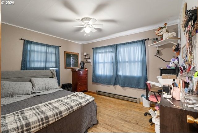 bedroom with ornamental molding, baseboard heating, ceiling fan, and wood finished floors