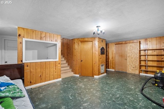 additional living space with stairway, wooden walls, a textured ceiling, and baseboards