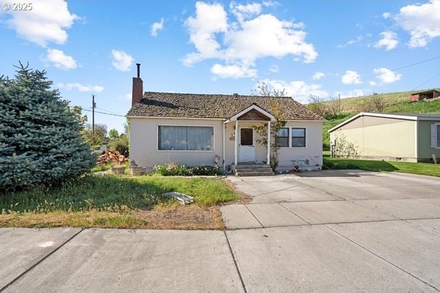 bungalow-style home with a chimney and stucco siding