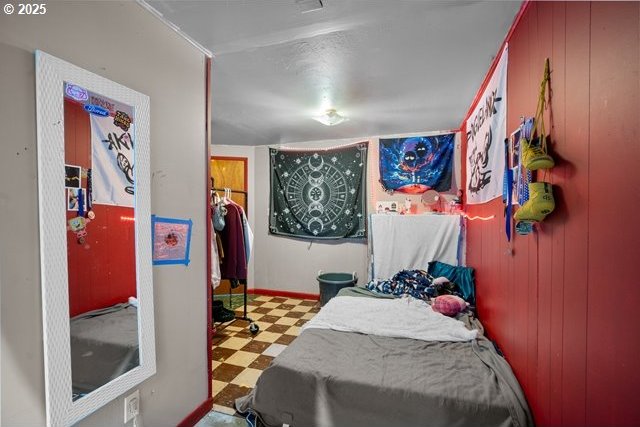 bedroom with wood walls and tile patterned floors
