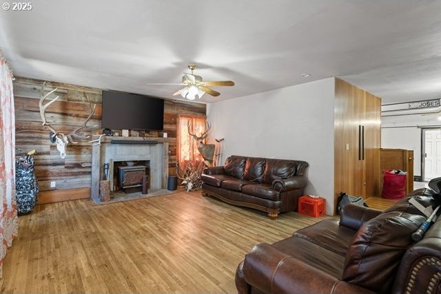 living room featuring wood walls, wood finished floors, and ceiling fan