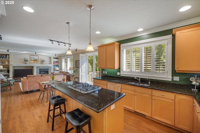 kitchen featuring appliances with stainless steel finishes, light wood-type flooring, a sink, and a kitchen island