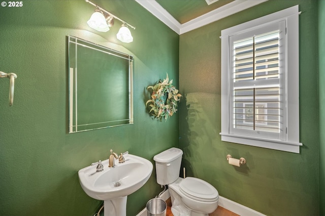 half bathroom featuring baseboards, a sink, toilet, and crown molding
